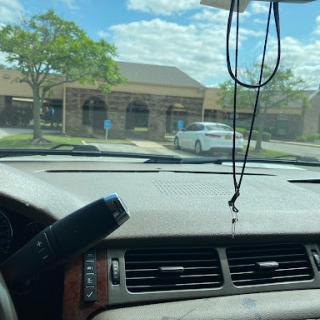 View from the inside of a car parked in front of a building on a cloudy day.