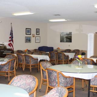 A quiet dining area with multiple tables and chairs, decorated with an American flag and framed pictures on the wall.