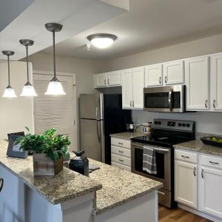 A modern kitchen with white cabinets, granite countertops, and stainless steel appliances.