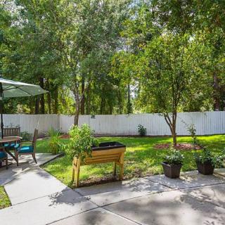 A tranquil backyard with a garden and patio area under the sunny sky.
