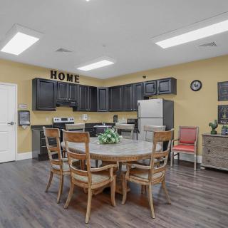 A cozy kitchen and dining area featuring a round table and chairs, with black cabinets and a refrigerator.
