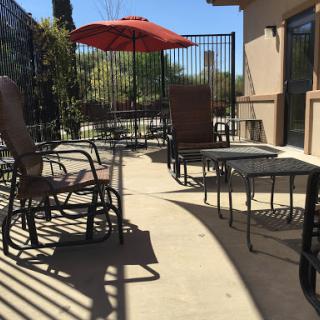 A sunny outdoor patio area featuring lounge chairs and an umbrella.