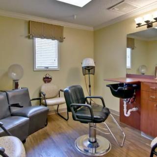 A cozy hair salon interior with a barber chair, large mirror, and dryer chairs.