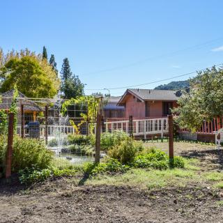 A rustic house with a garden and fence in a rural setting.