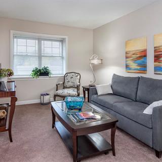 A cozy living room with a sofa, coffee table, and artwork on the wall.