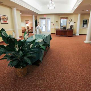 A spacious lobby with a reception desk, indoor plants, and comfortable seating.