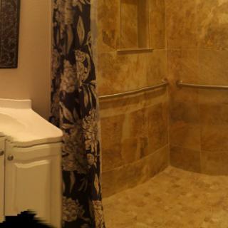 A bathroom featuring a tiled walk-in shower and a white sink with a floral curtain.