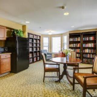 A cozy library space with bookshelves, tables, and chairs for reading.