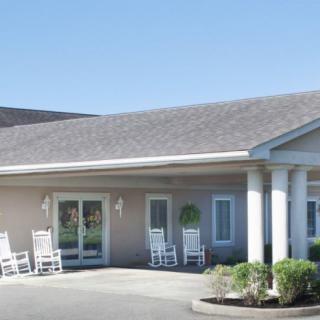 A building with a front porch featuring rocking chairs and columns.
