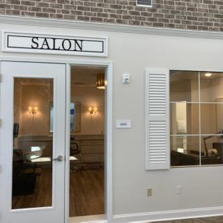 A salon entrance with glass doors and a large window pane.