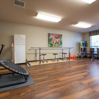 A spacious exercise and rehabilitation room equipped with a barre and fitness equipment.