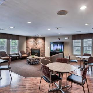 A cozy lounge area featuring a television, fireplace, and seating arrangements with tables and chairs.