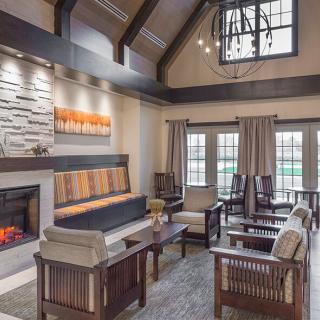 A modern living room with a cozy fireplace and high ceilings, featuring wooden beams and comfortable seating.