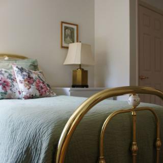 A cozy bedroom with floral pillows and a vintage brass bed frame.