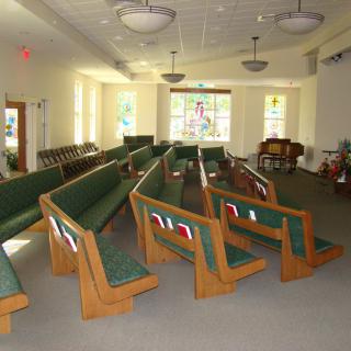 Interior view of a church with wooden pews and stained glass windows.