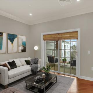 A cozy and modern living room featuring a stylish white sofa, contemporary artwork, and abundant natural light from large windows.