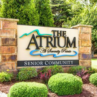 Entrance sign for The Atrium Senior Community surrounded by landscaped greenery.