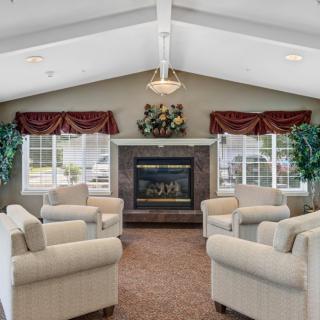 A cozy lounge area featuring comfortable armchairs arranged around a fireplace.