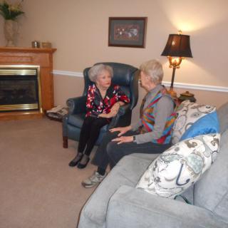 Two elderly women sitting in a cozy living room, engaged in conversation.