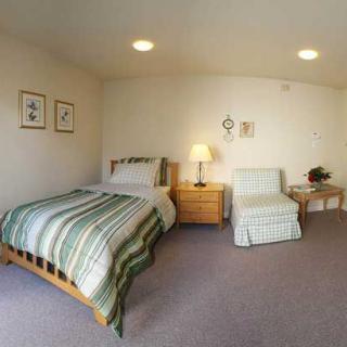 A cozy bedroom with a single bed, armchair, and subtle decor.