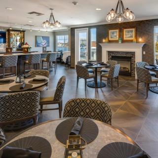 A cozy restaurant interior with a dining area featuring tables, chairs, a bar counter, and a fireplace.