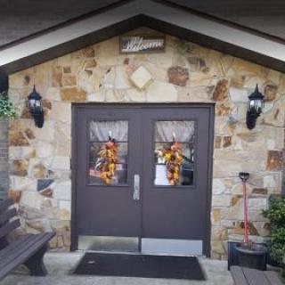 A welcoming entrance with stone walls and autumn-themed decorations on double doors.
