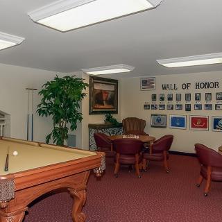 A meeting room featuring a pool table, chairs, and a 'Wall of Honor' display.
