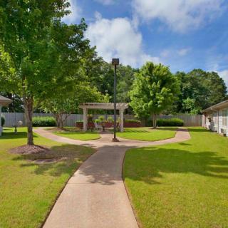 A scenic garden with a winding pathway surrounded by trees and lush greenery.
