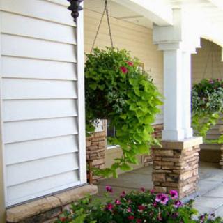 A serene porch adorned with hanging plants and colorful flowers, showcasing a welcoming home exterior.