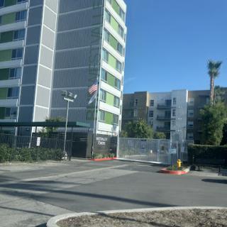 A view of a modern apartment building with a gated entrance and an American flag.