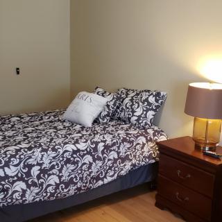 A cozy bedroom with a patterned bedspread and a nightstand with a lamp.