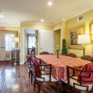 A warm and inviting dining room with a long table and chairs, decorated with artwork and bright lighting.