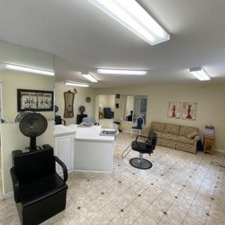 A well-lit hair salon interior featuring styling chairs, mirrors, and a comfortable waiting area with a sofa.