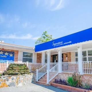 The entrance of a hotel featuring a blue awning under a clear sky.