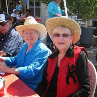 Two women enjoying a sunny day at an outdoor event, both wearing stylish hats.