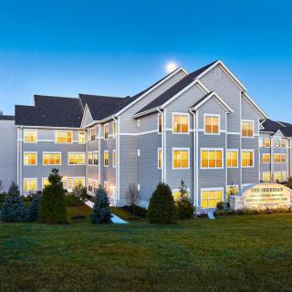 A well-lit hotel building at dusk with manicured lawns.
