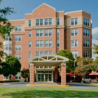 A multi-story brick hotel with a welcoming entrance surrounded by trees.