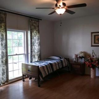 A minimalist bedroom with a single bed, wooden flooring, and a window with patterned curtains.