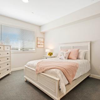 A cozy bedroom with neutral tones featuring a bed and dresser.