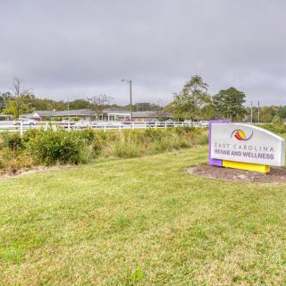 A roadside sign in a grassy area with a cloudy sky backdrop.