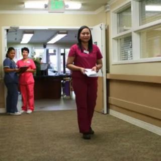 A nurse walking down a hospital corridor with colleagues in the background.