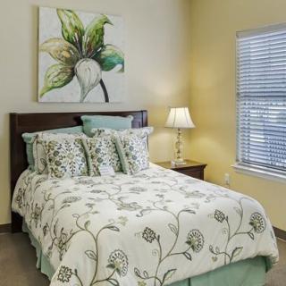 A cozy bedroom with floral bedding and a decorative lamp beside the bed.
