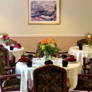 A cozy dining room with elegantly set tables and floral arrangements.