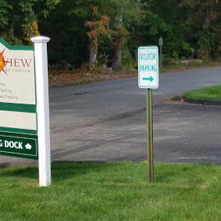 A directional sign on a roadside leading to a dock area.