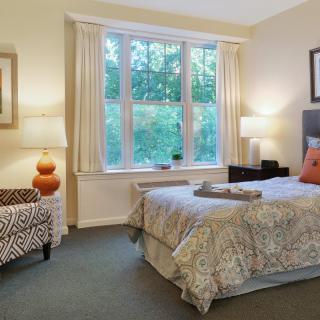 A cozy bedroom with a large window, bed, and elegant decor.