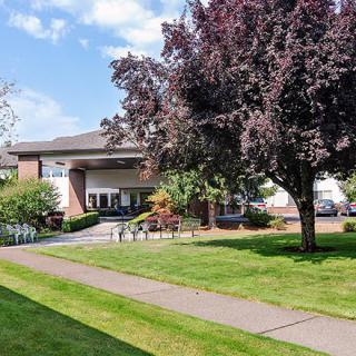 A building surrounded by lush trees and well-maintained lawns under a clear sky.