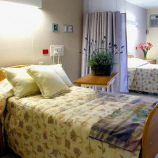 A clean and comfortable hospital room with two beds, curtains, and floral decor.