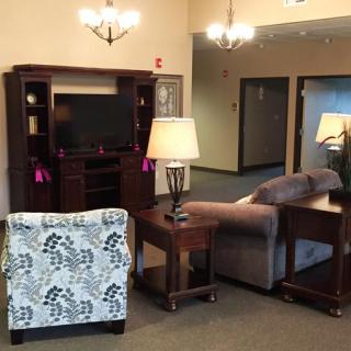 A cozy living room setup with a sofa, armchair, table lamps, and a TV stand.