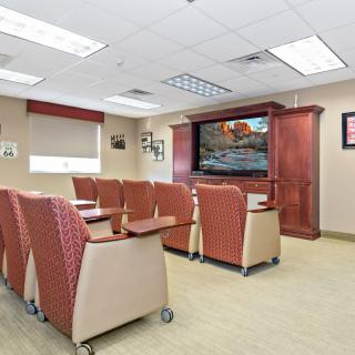 A modern conference room with comfortable seating and a large television.