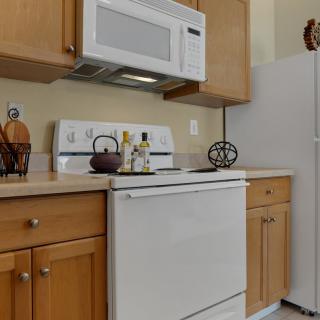 A kitchen with wooden cabinets, a stove, microwave, and refrigerator.